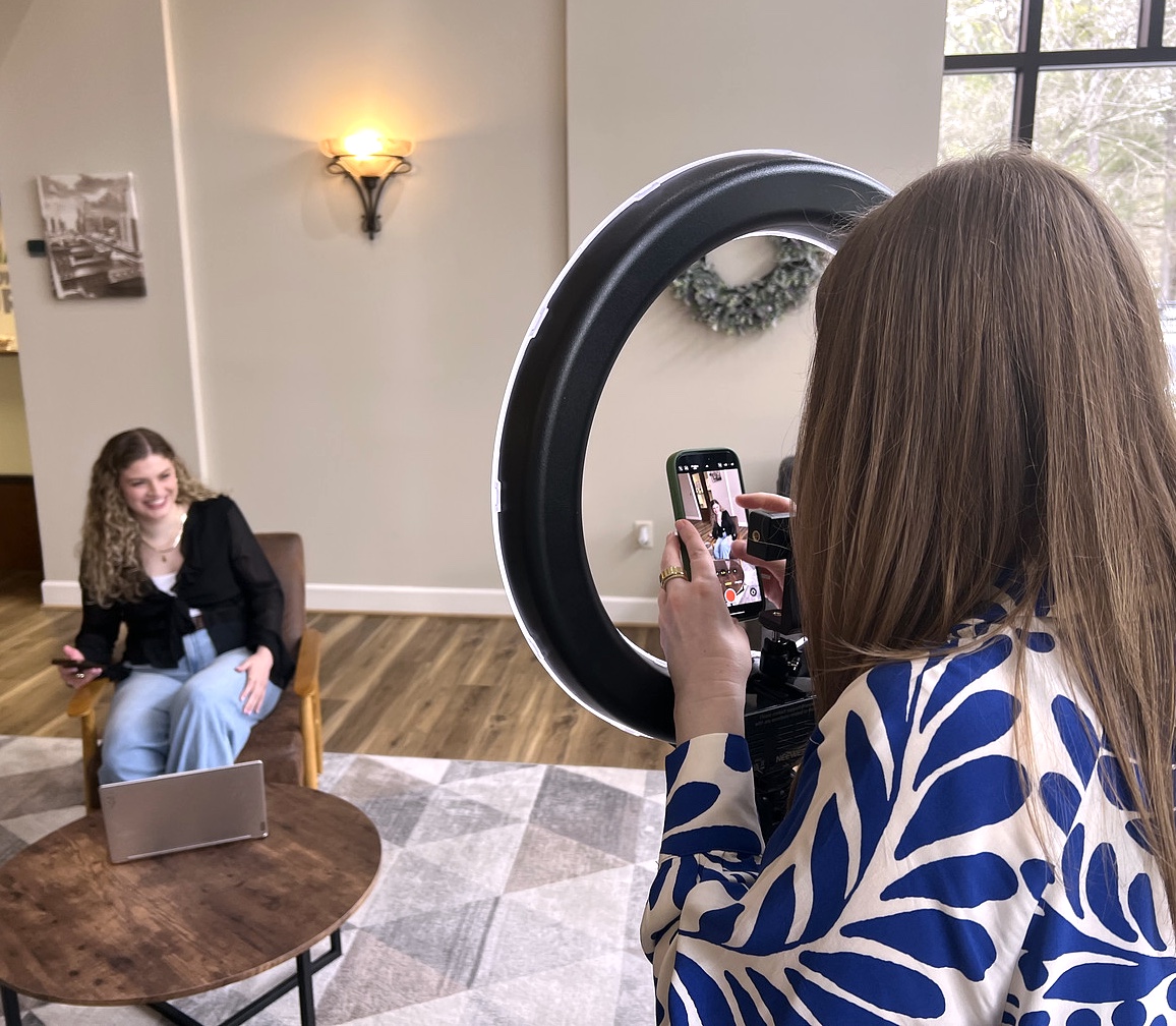 Christina Colantonio taking a video of Kylee Veres with a ring light in an office setting.