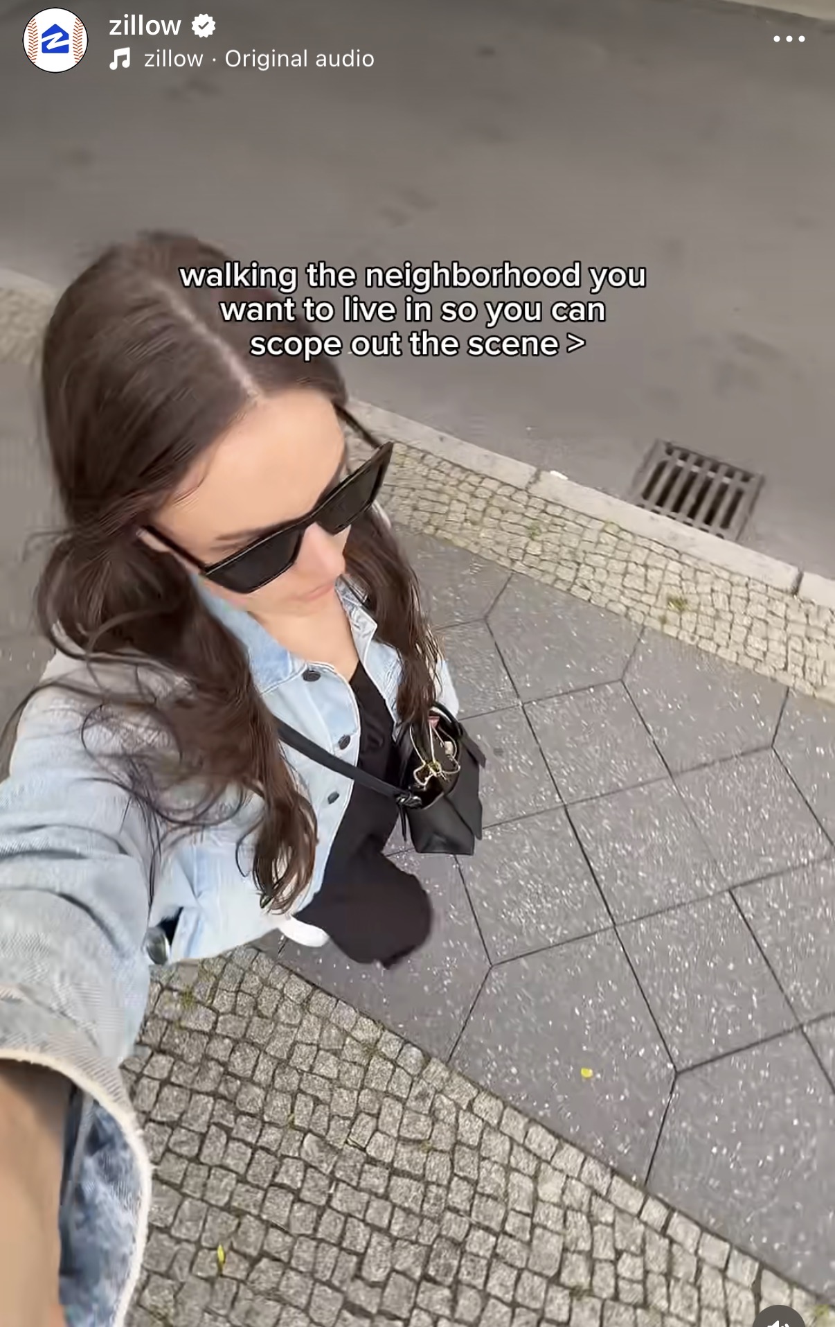 Girl walking on street holding up her phone, showcasing Zillow's 
